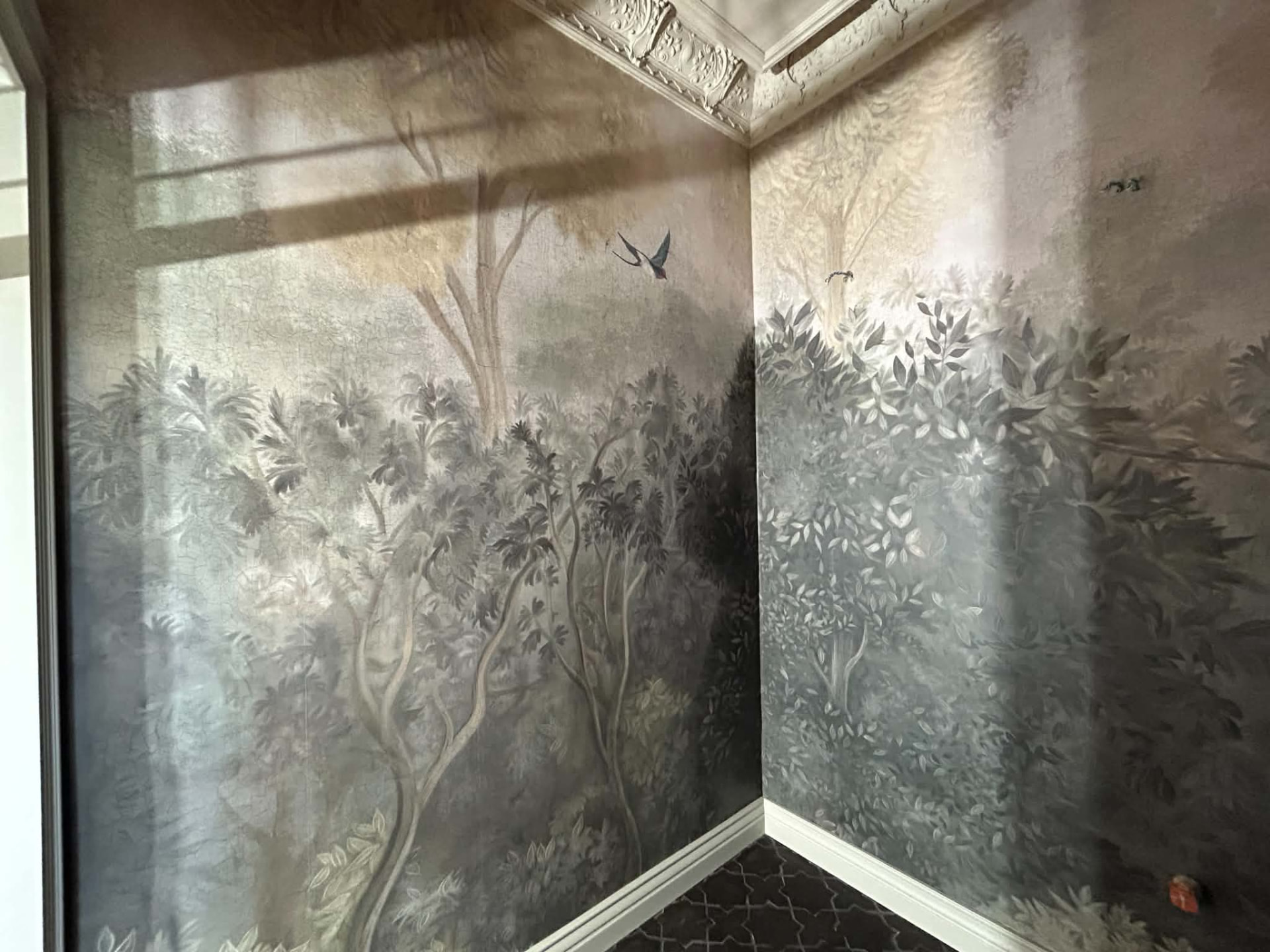 Panoramatapet med trädmotiv och fågel i rum med stuckatur och vita golvlister